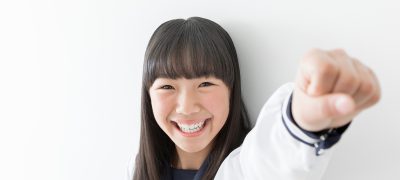 国語が苦手だったが、英才塾で学んだおかげで、進学校で成績が上がりガッツポーズをしている中学生。