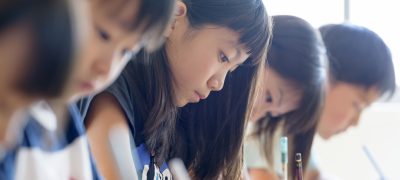 試験で記述問題を解いている受験生が、机で考え込んでいる様子