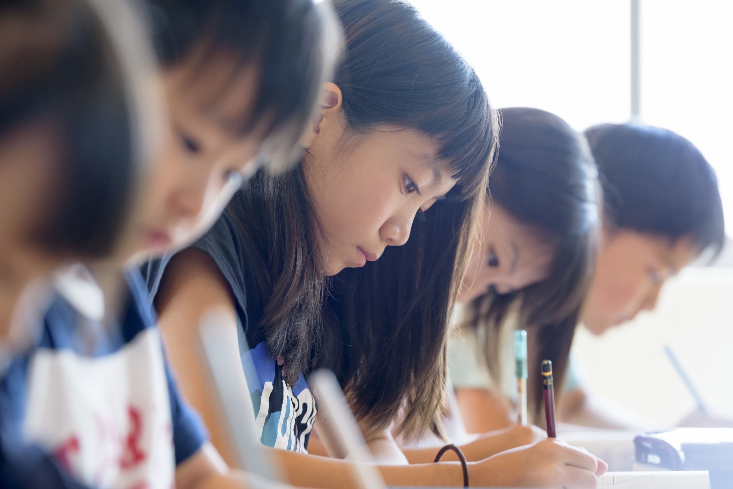 試験で記述問題を解いている受験生が、机で考え込んでいる様子